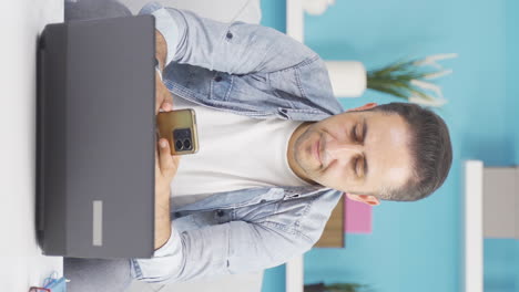 Vertical-video-of-Man-using-laptop-nervously-talking-on-the-phone.